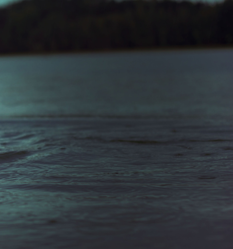 Koristekuva, nainen uimassa järvessä sateella.